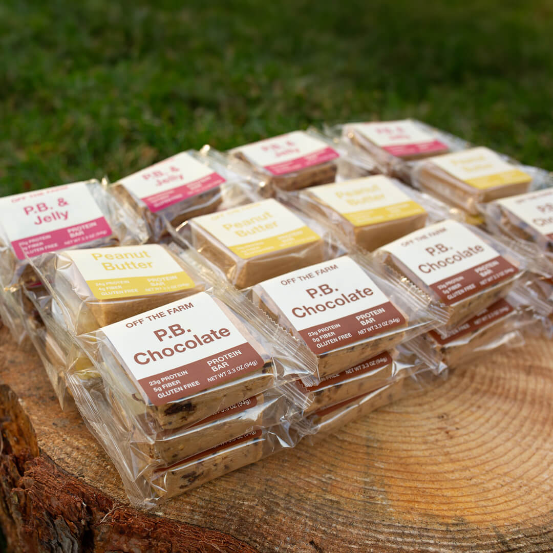 Packaged protein bars on a wooden surface with grass in the background