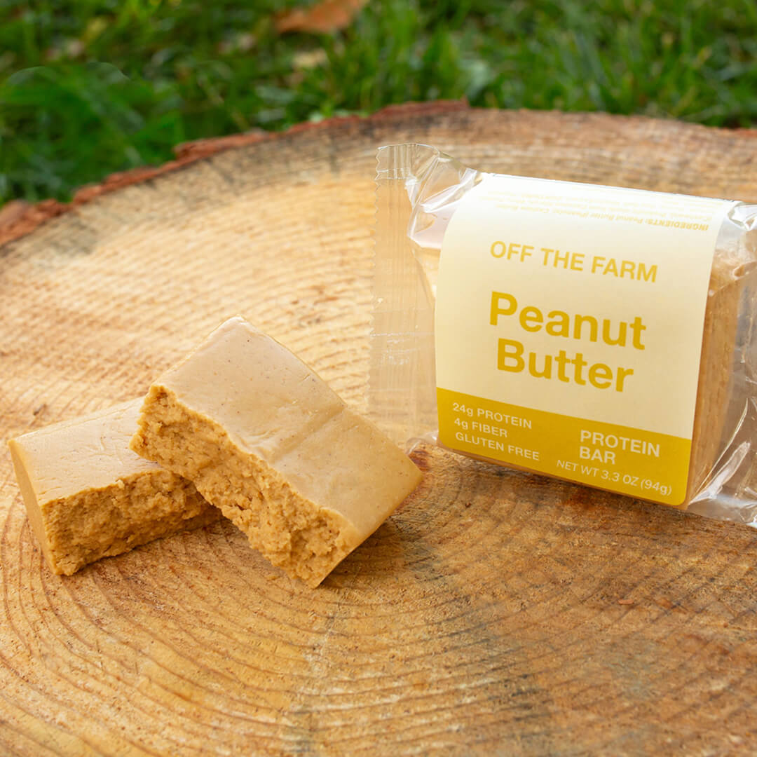 Peanut butter protein bar with packaging on a wooden surface outdoors