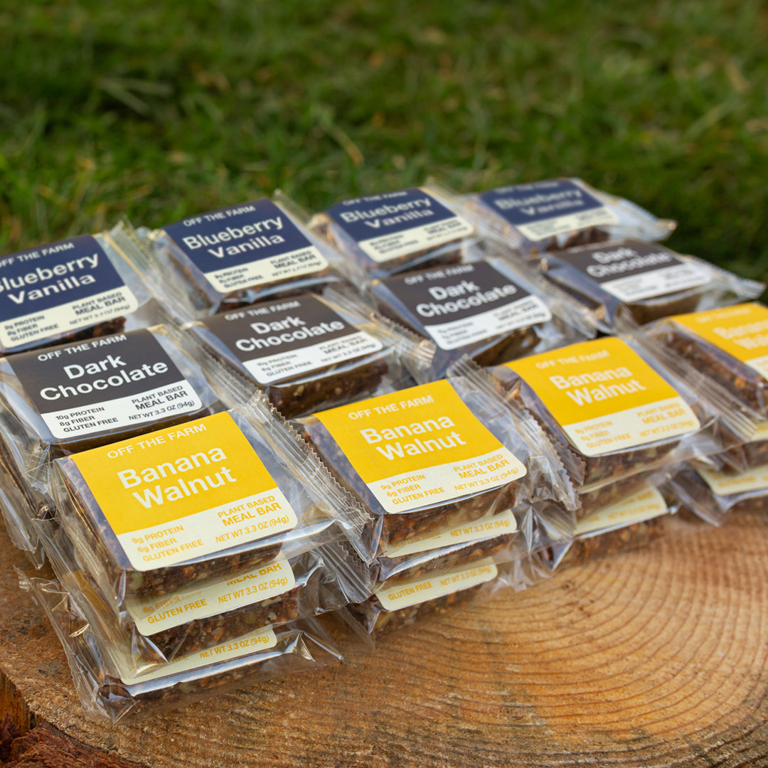 Packaged meal bars with various flavors on a wooden surface outdoors.