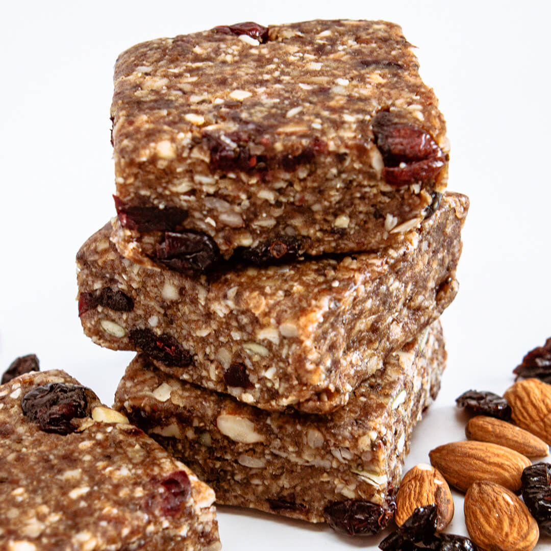 Stack of cranberry almond energy bars with nuts and raisins on a white background