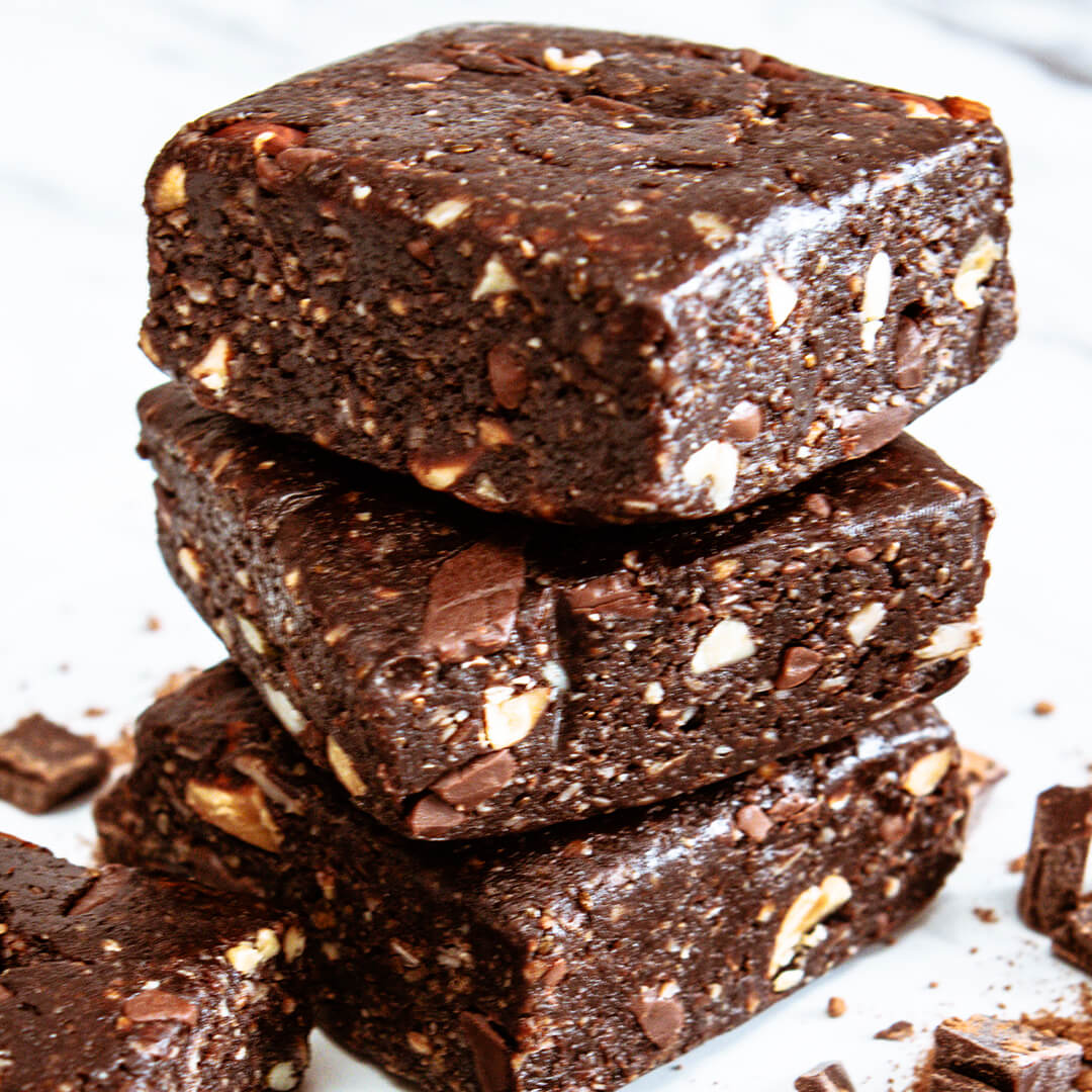 Stack of dark chocolate meal bars with nuts on a white background