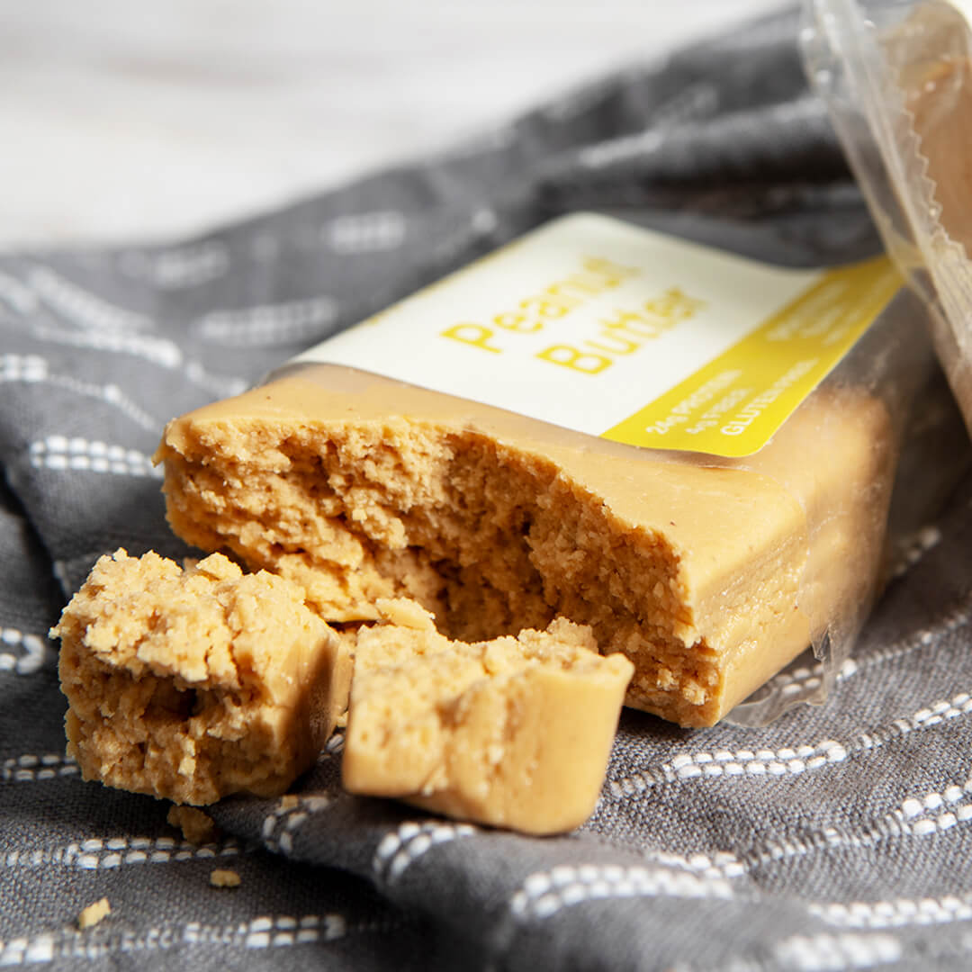 OFF THE FARM peanut butter protein bar broken up on a gray patterned towel