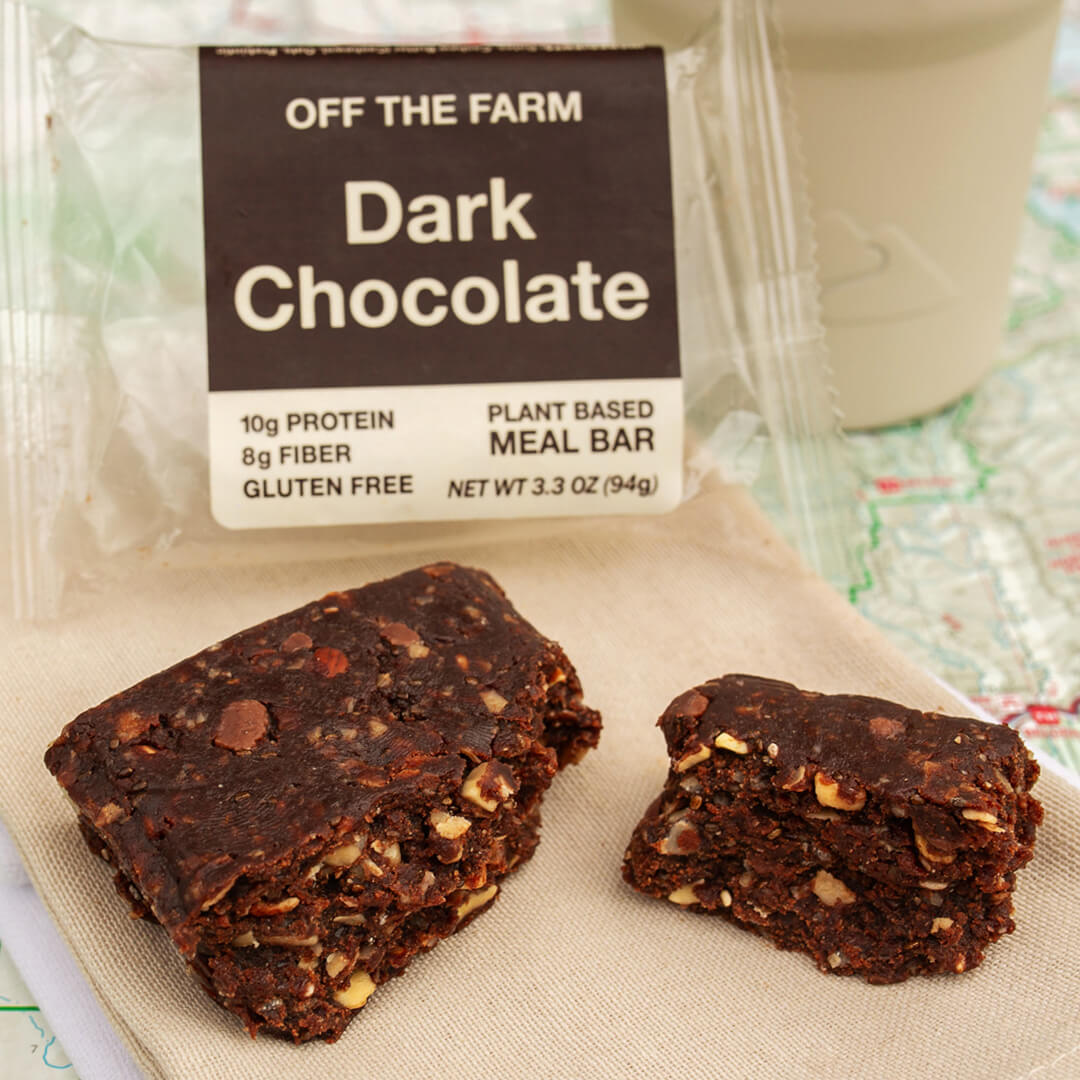 Dark chocolate meal bar with packaging labeled 'Off The Farm Dark Chocolate' on a textured surface.