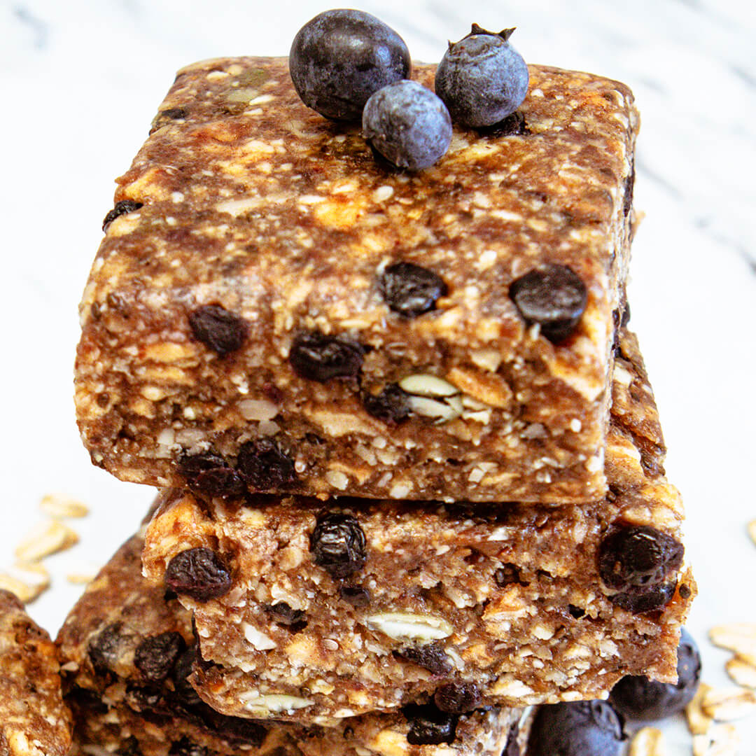 Stack of wild blueberry meal bars with blueberries on a white background