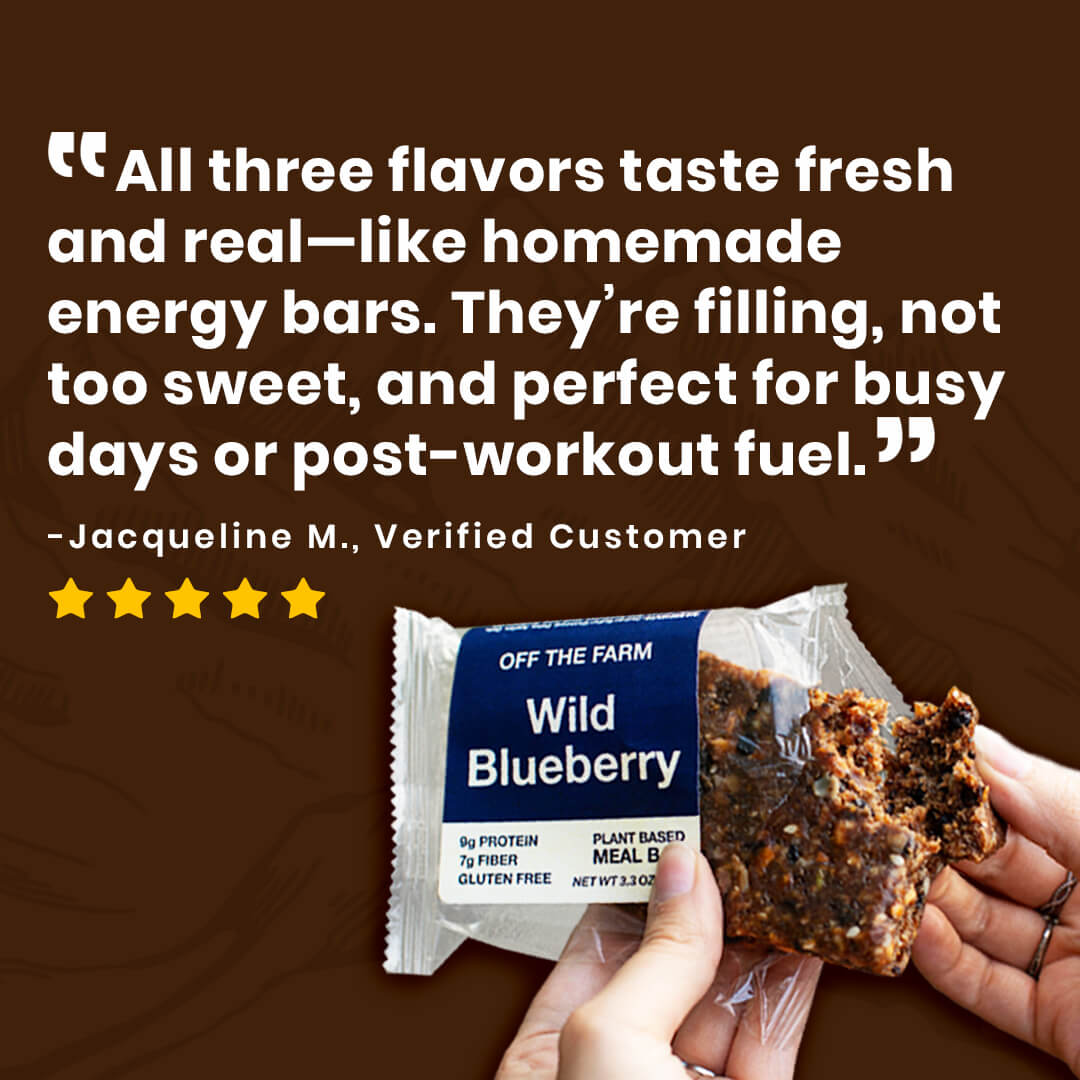 Hand holding a Wild Blueberry energy bar with a customer review on a brown background