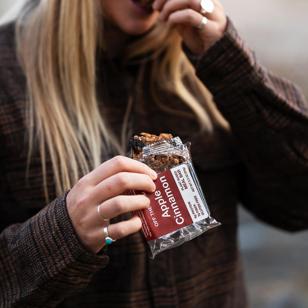 Person holding an OFF THE FARM apple cinnamon meal bar