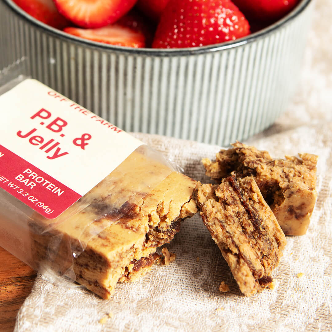 P.B. & Jelly protein bar broken up, next to a bowl of strawberries.