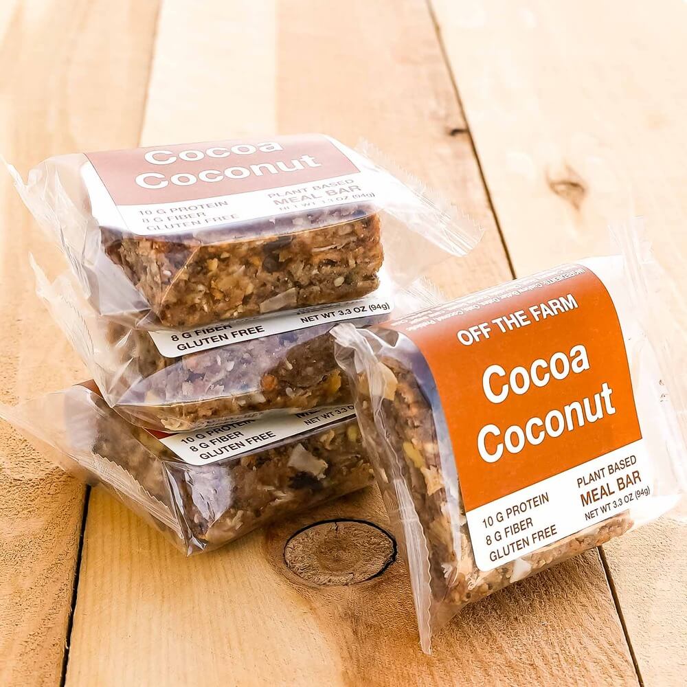 Off The Farm Cocoa Coconut meal bars in clear packaging on a wooden surface