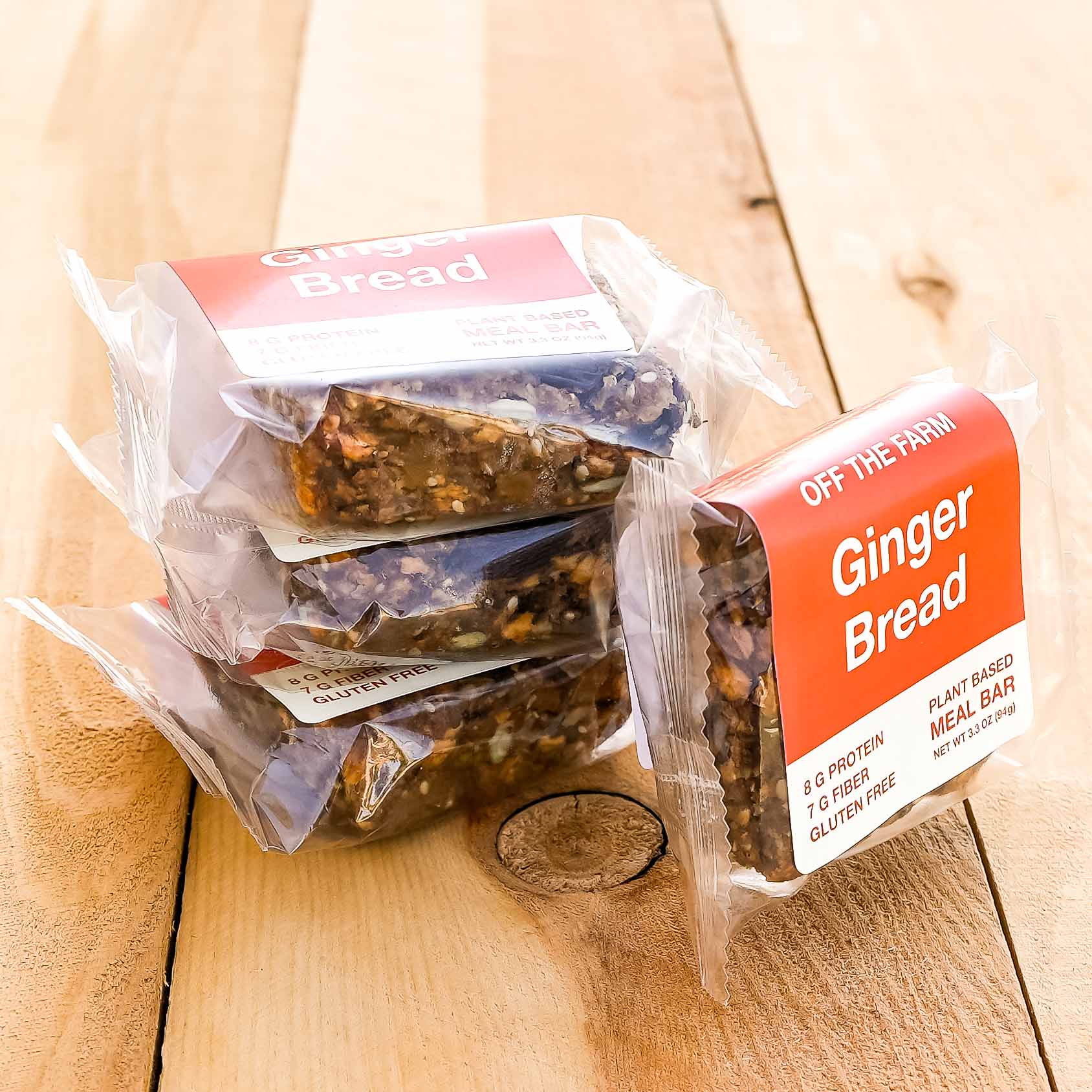 Packaged ginger bread meal bars with the label 'OFF THE FARM Bread' and 'Ginger Bread' visible, placed on a wooden surface.