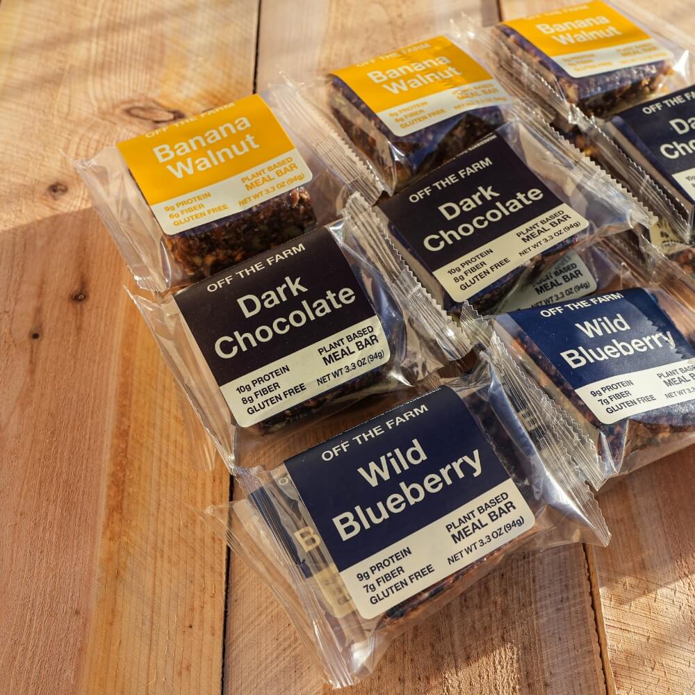 Banana Walnut, Dark Chocolate and Wild Blueberry meal bars sitting on a wood table.