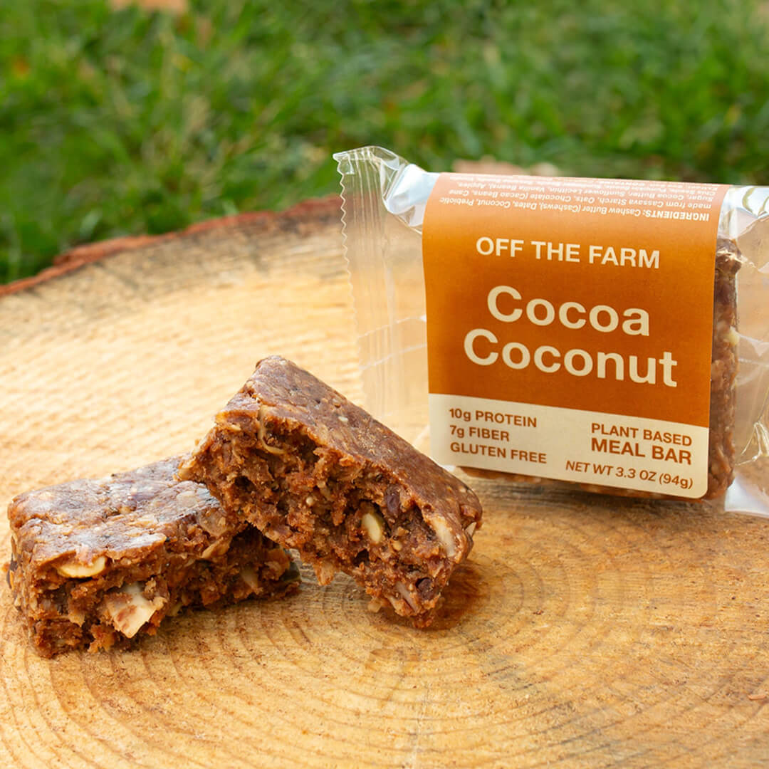 Cocoa Coconut meal bar from Off The Farm on a wooden surface with grass in the background