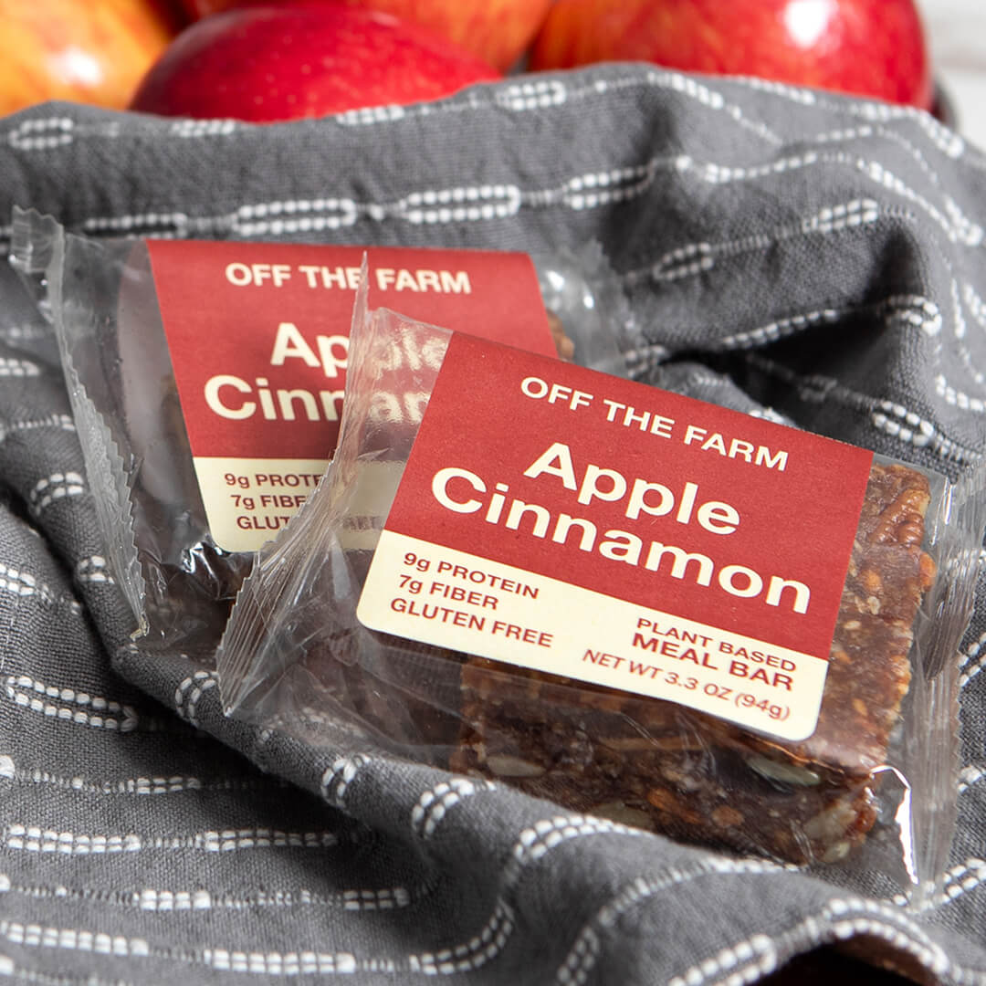 Apple Cinnamon meal bars with 'Off The Farm' label on a gray fabric background