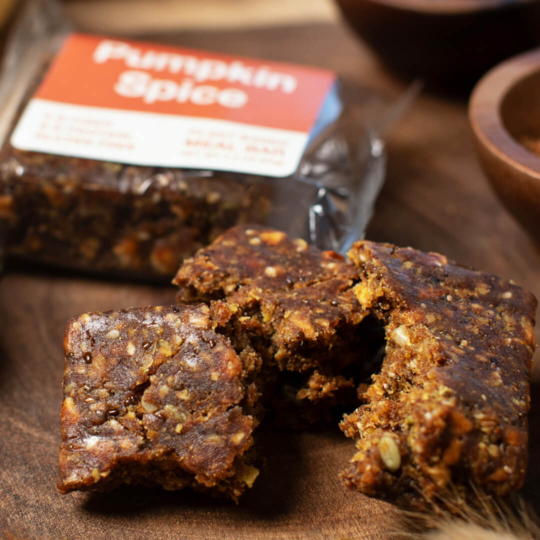 Pumpkin spice-flavored meal bars on a wooden surface with a package in the background.