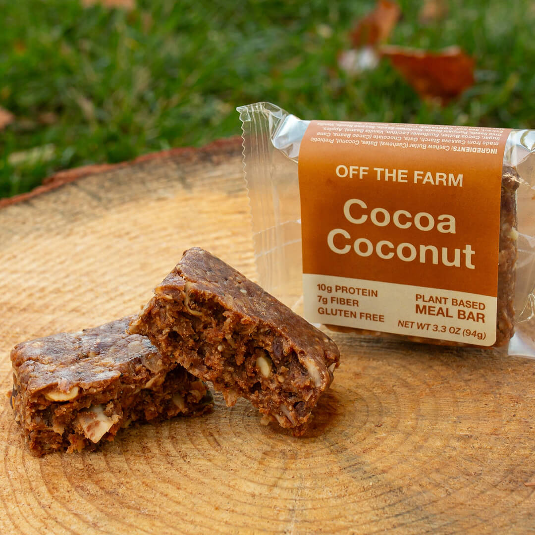 OFF THE FARM Cocoa Coconut meal bar with packaging on a wooden surface outdoors