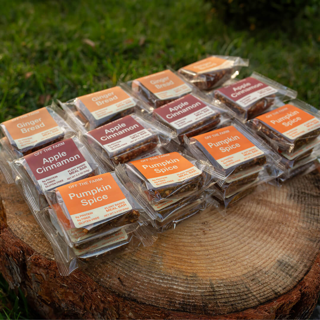 Assorted OFF THE FARM holiday meal bars on a wooden surface with grass in the background.