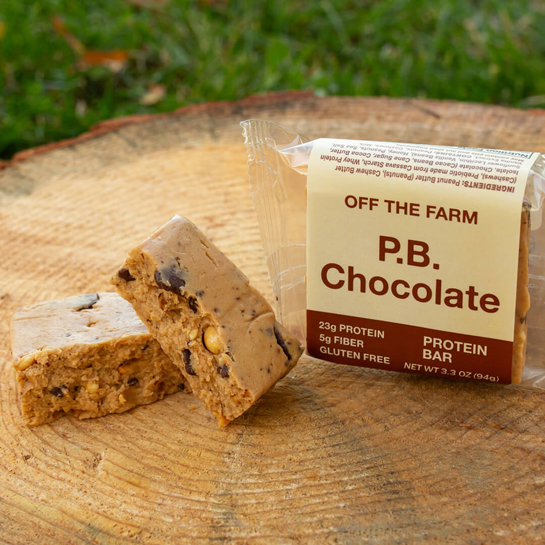 Protein bar with packaging labeled 'Off The Farm P.B. Chocolate' on a wooden surface.