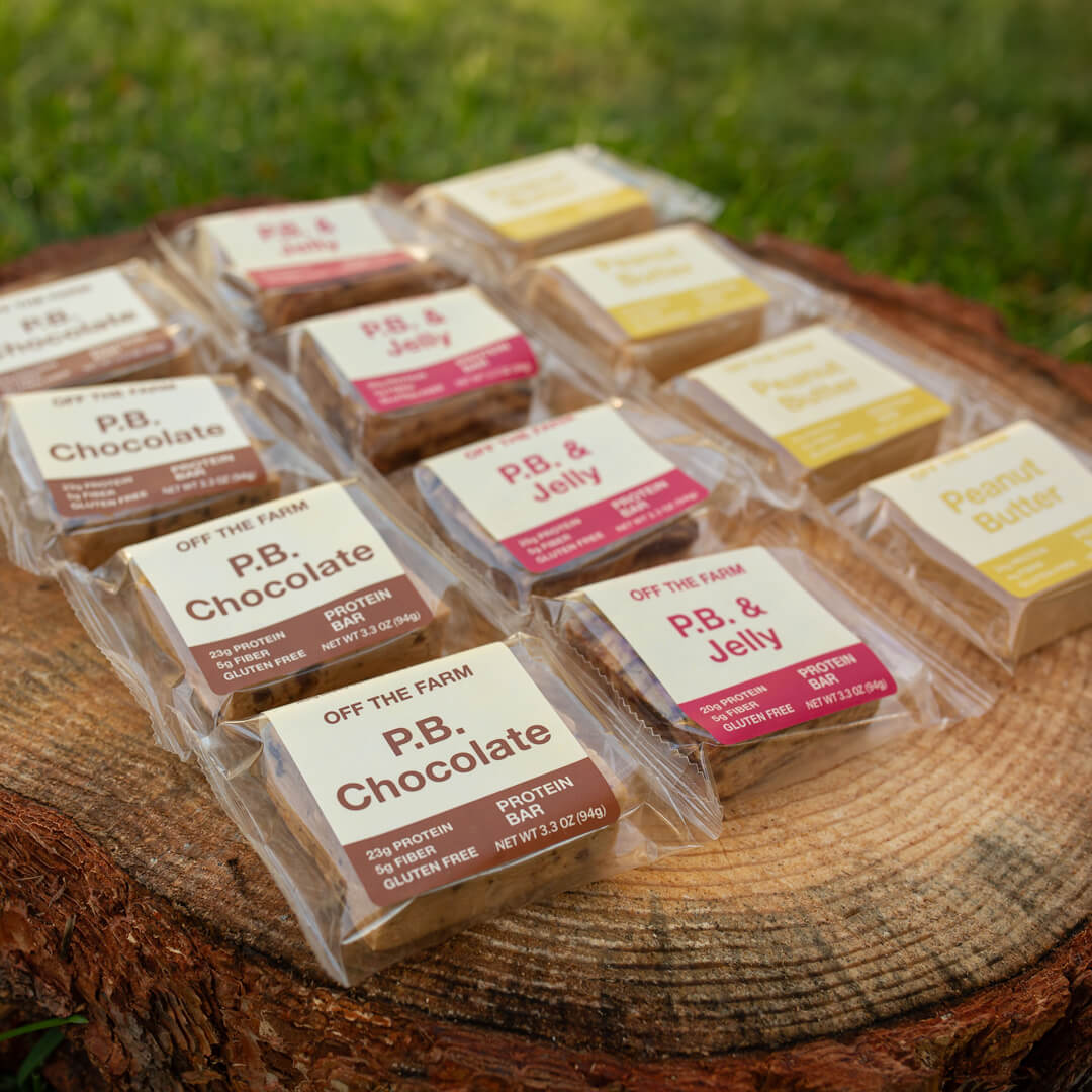 OFF THE FARM mixed peanut butter protein bars on log with grass in the background